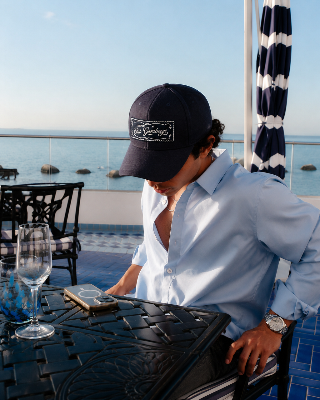 Homme portant la casquette Gamberge Club bleu marine de profil au bord de la Méditerranée.