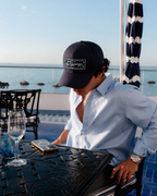 Homme portant la casquette Gamberge Club bleu marine de profil au bord de la Méditerranée.