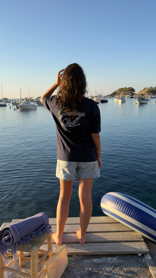 Femme portant le dos du t-shirt Gamberge Club bleu marine avec imprimé Gamberge Club.