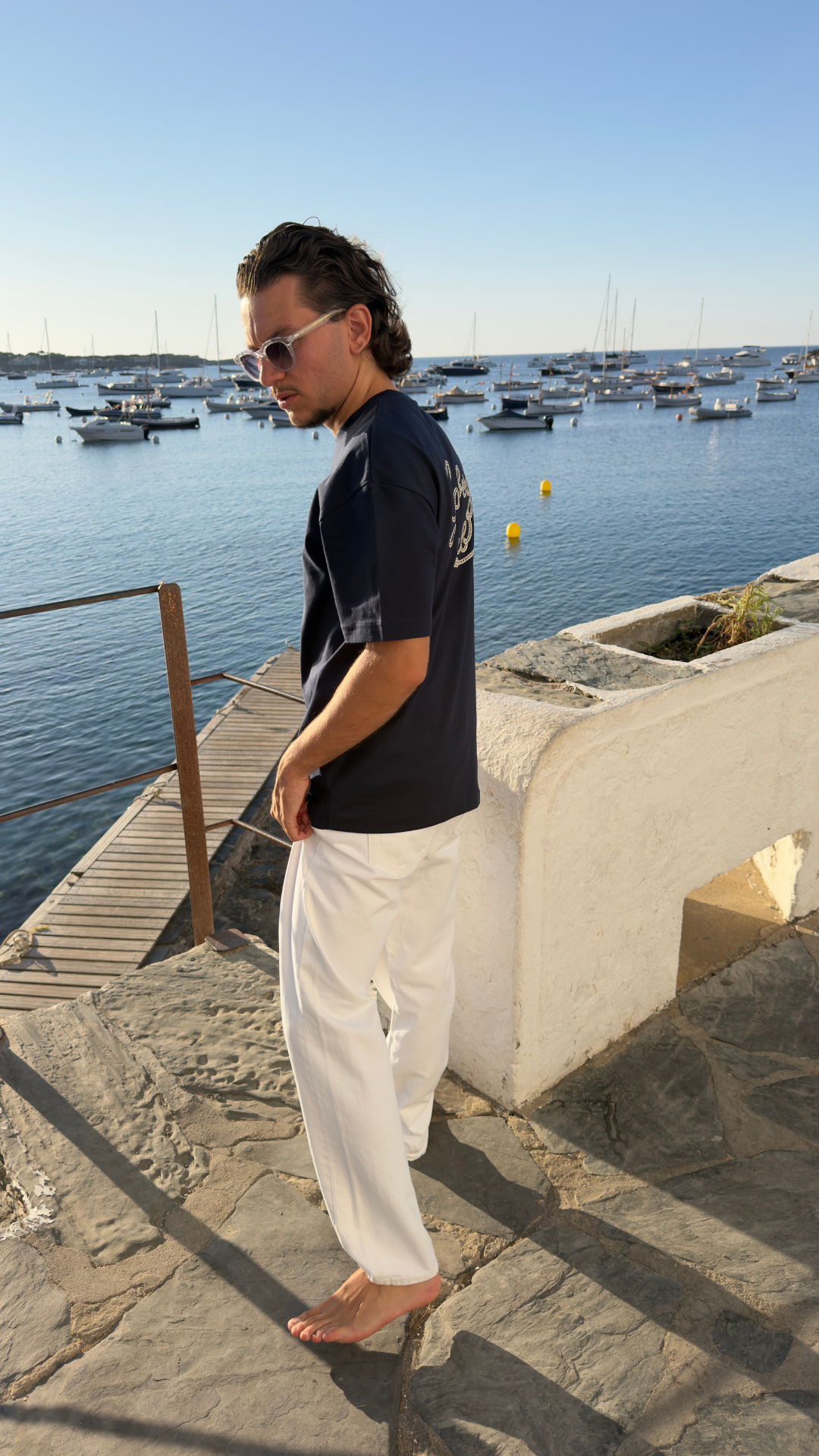 Homme portant le t-shirt Gamberge Club bleu marine de profil au bord de la Méditerranée.