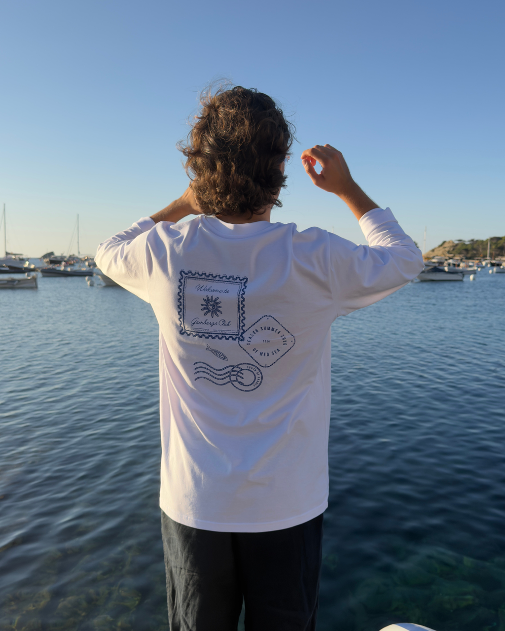 Homme portant le t-shirt manches longues Welcome to Gamberge Club au bord de la Méditerranée.