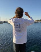 Homme portant le t-shirt manches longues Welcome to Gamberge Club au bord de la Méditerranée.